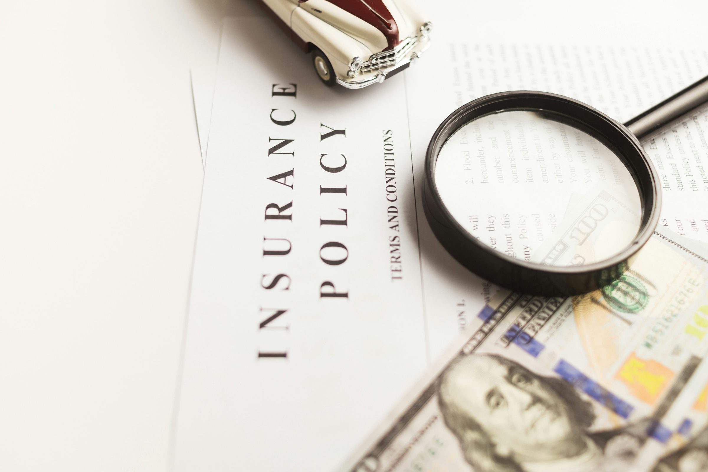 Magnifying glass on an insurance policy. Photo: Vlad Deep / Unsplash