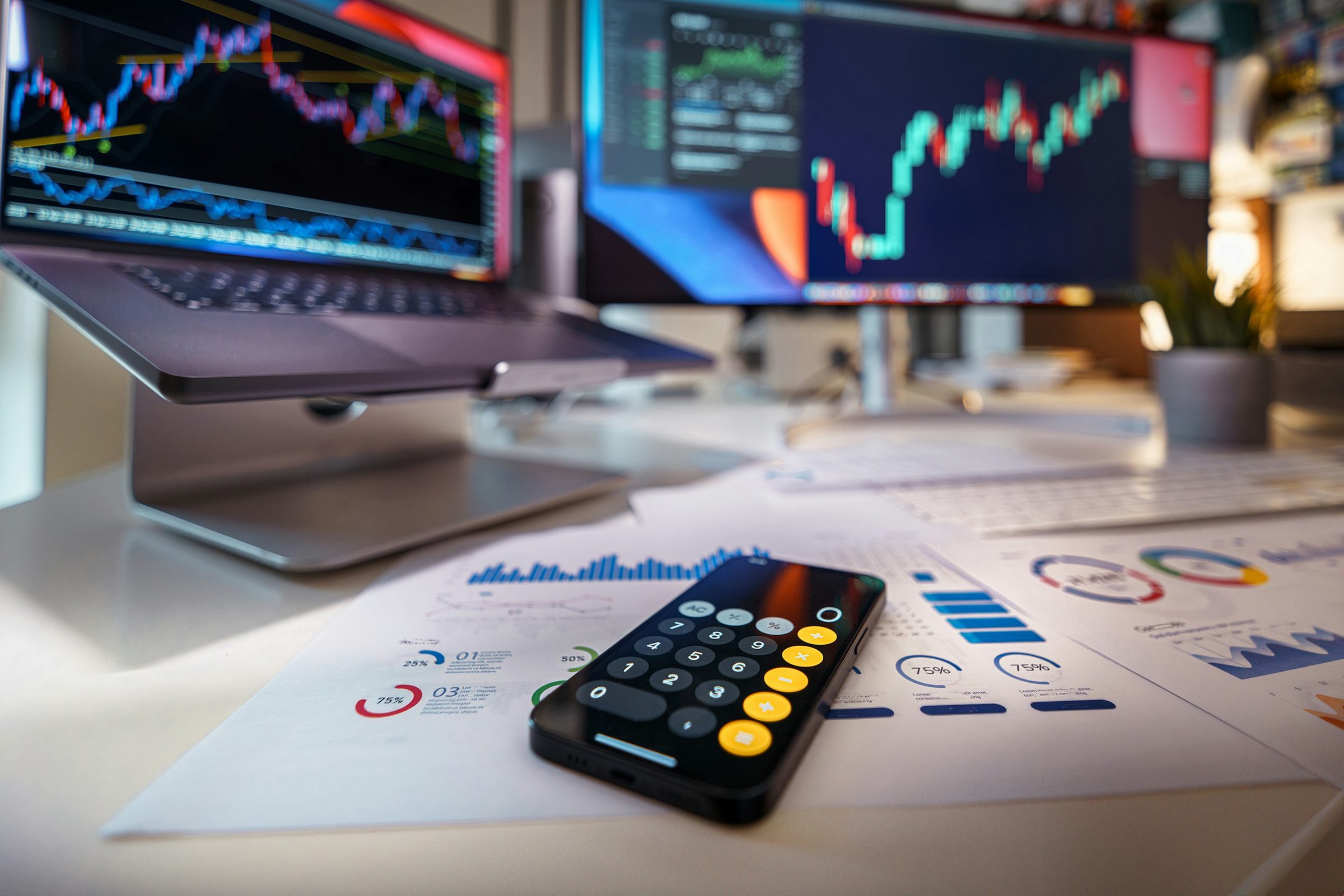 Calculator on a desk with financial charts. Photo: Jakub Żerdzicki / Unsplash